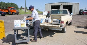 Unused pesticide being collected by a person and loading it to the bed of a pickup truck