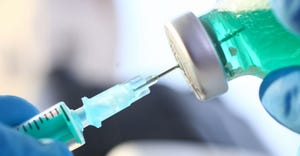 Clos- up of a syringe being placed into a vial by gloved hands