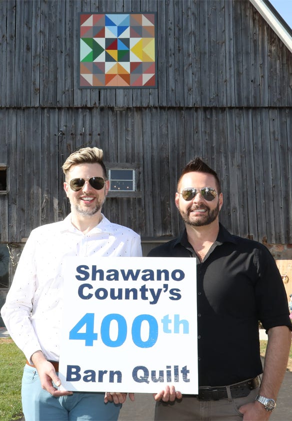 Mark Hebert and Steven Krueger stand in front of their barn displaying Shawano County’s 400th barn quilt 