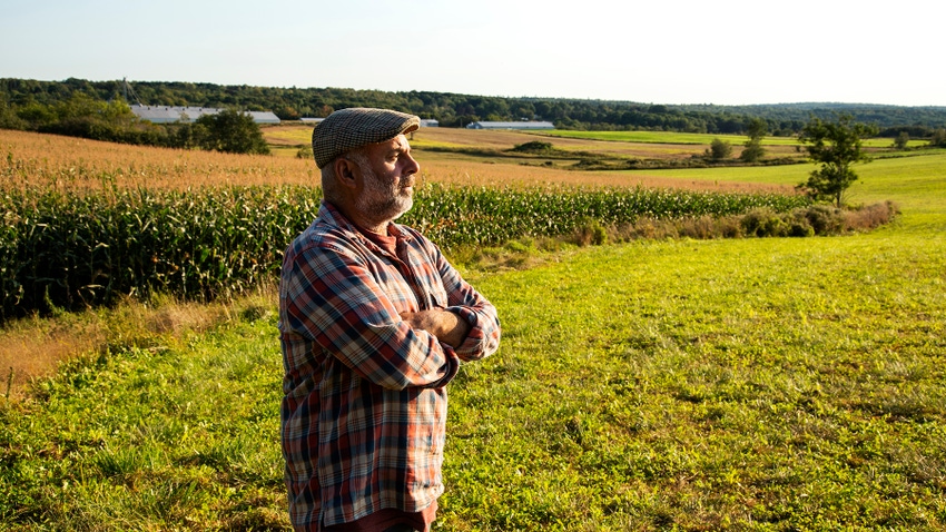 Farmer standing in field thinking