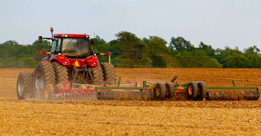 red six wheel tractor plowing an agricultural field