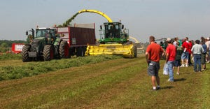 A group of people watching tractors at work in a field