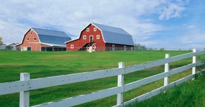 Red barn with a white wooden fence on the pasture perimeter