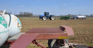 A blue tractor spraying a cornfield