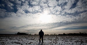 A Wisconsin farmer stands out in his snow-dusted cornfield in the low winter sun.