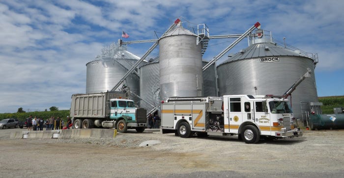 grain bin center with semi and fire truck parked in front