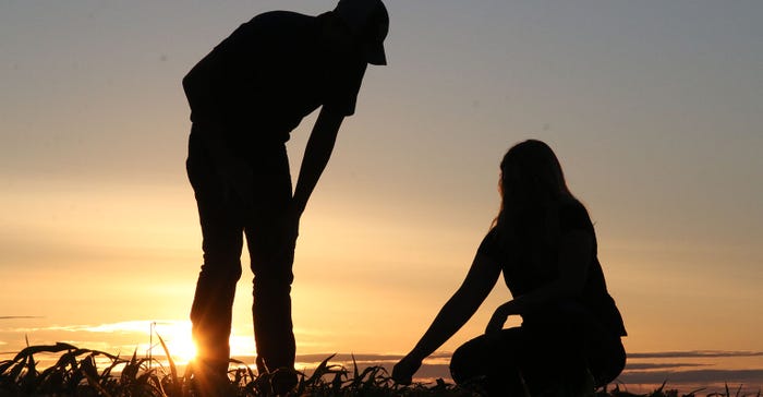 Photo of man and woman in corn field in evening light.