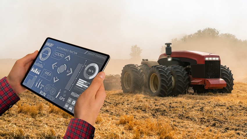 A farmer with digital tablet controls an autonomous tractor
