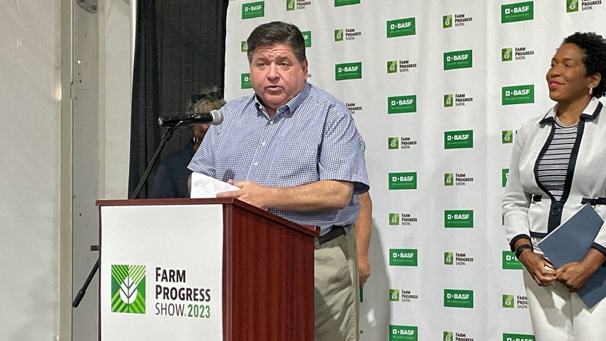 Governor JB Pritzker stands behind a podium and speaks into a microphone at Farm Progress Show 2023
