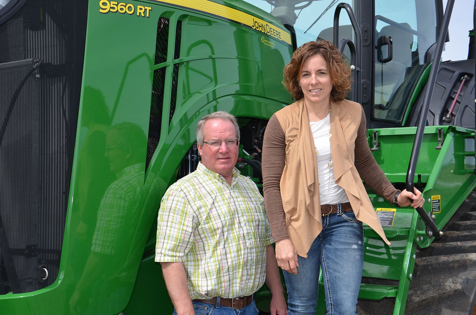 John and Kristi Kretzmeier pose next to a 9560 RT John Deere tractor
