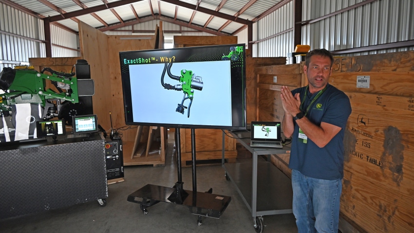 Jesse Haecker stands near a TV while he explains John Deere's Exact Shot technology