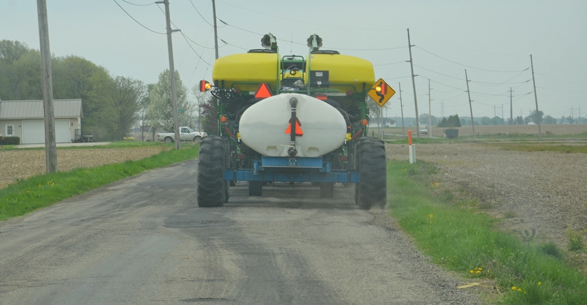 driving down rural road behind tractor and planter 