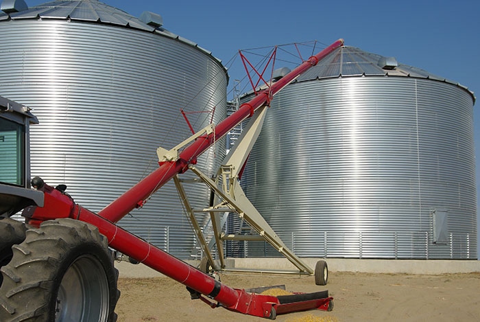 Auger connected to tractor unloading into grain bin