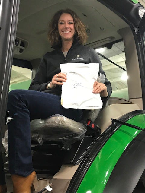 Jean Payne holding a lease while sitting in a tractor cab