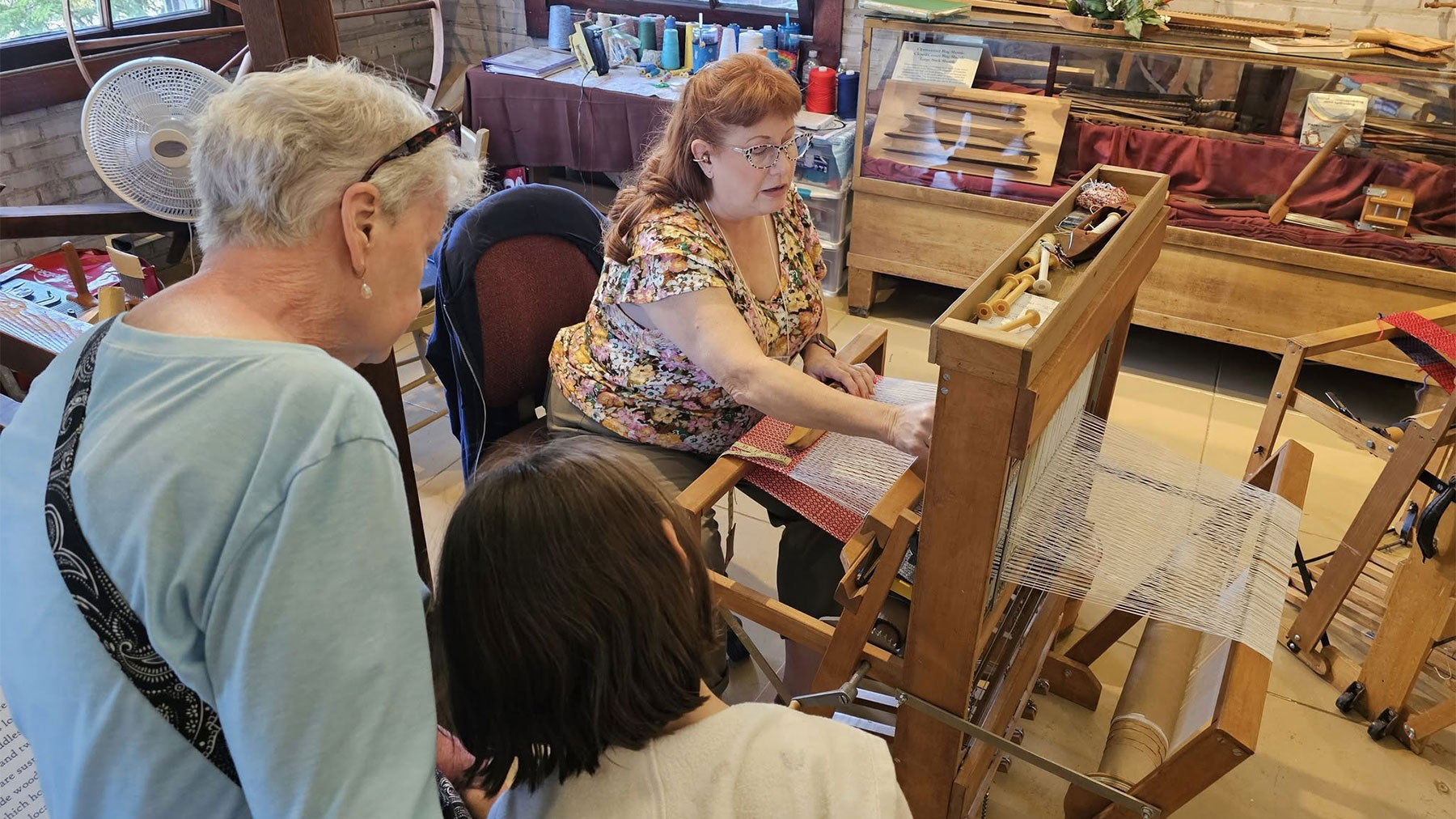 Roger Thomas - Two people watch a weaving demonstration