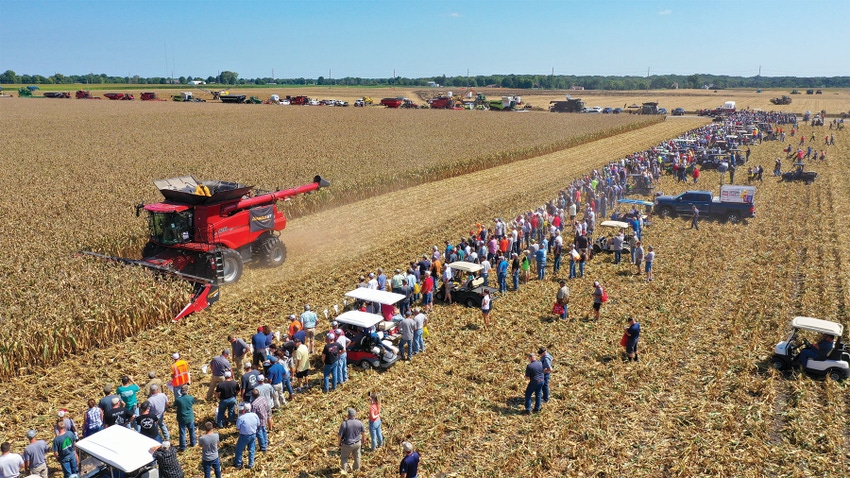 aerial view of farm show visitors lined up to watch a combine harvest corn