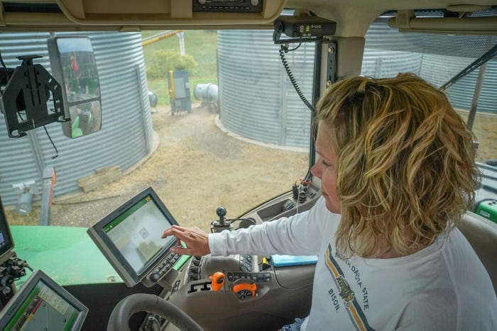 A woman reading a digital screen inside of a tractor