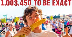 man eating corn on the cob with people in background