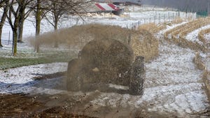 Rear view of a tractor spreading liquid manure on a winter day