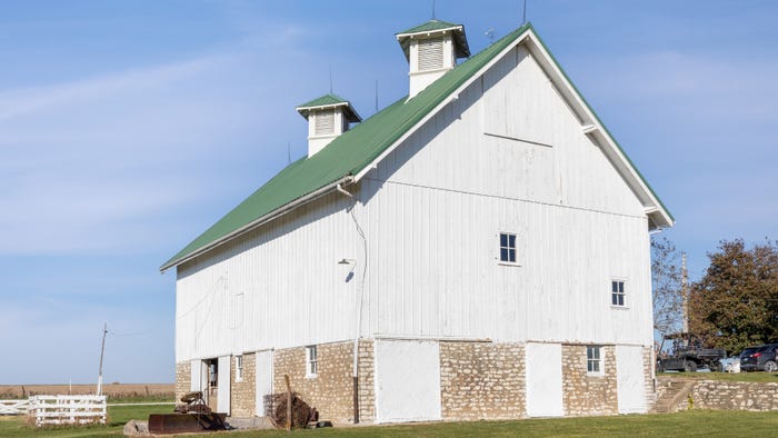 Large white barn with brick on first level Large white barn with brick on first level