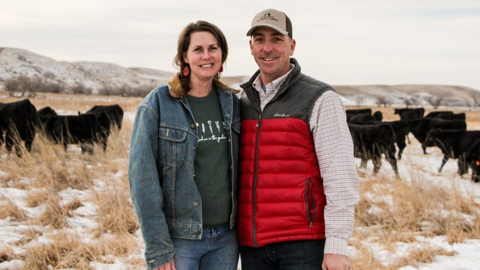 Shawn and Kristy Freeland in field with cattle behind them Shawn and Kristy Freeland in field with cattle behind them