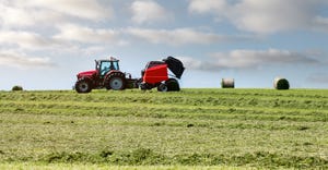 tractor and hay baler making bales of hay in field