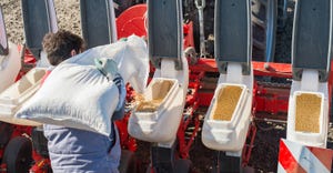 Farmer loads soybean seed into hoppers of the planter