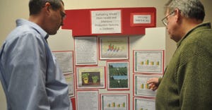 men looking at information at soybean expo