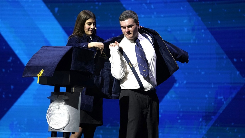 Jessica Herr placing a jacket on Grant Norfleet on a convention stage