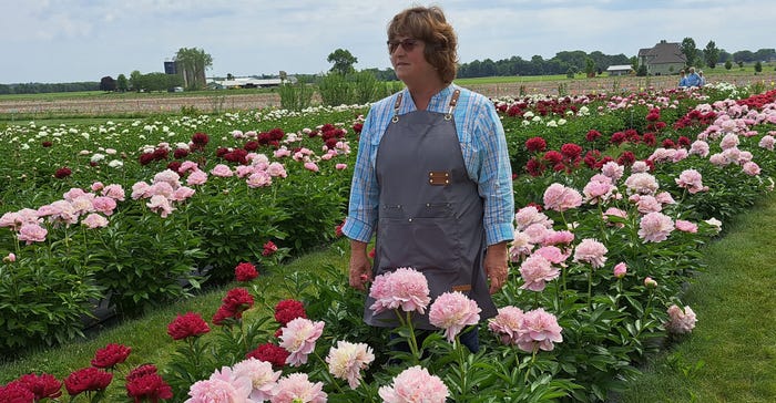 Michelle Ovans stands amid rows of peony plants at Ovans Peony Farm near Beaver Dam, Wis.
