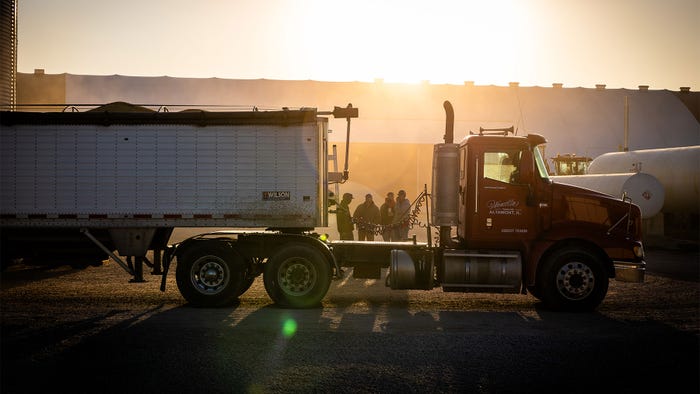 Farmers gather behind a semi truck during a sunrise