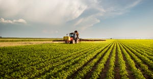 Tractor spraying pesticides on soy field