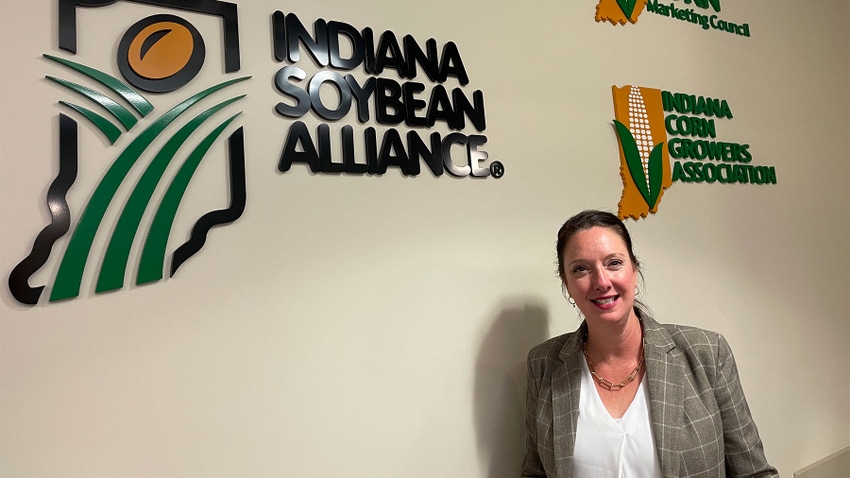 Courtney Kingery standing below the Indiana Soybean Alliance logo painted on a wall Courtney Kingery standing below the Indiana Soybean Alliance logo painted on a wall