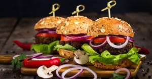 Three vegan burgers on a plate with garnish.