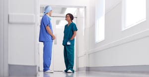 Doctor and nurse in scrubs talking in white sterile looking hallway