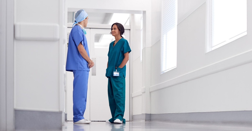 Doctor and nurse in scrubs talking in white sterile looking hallway