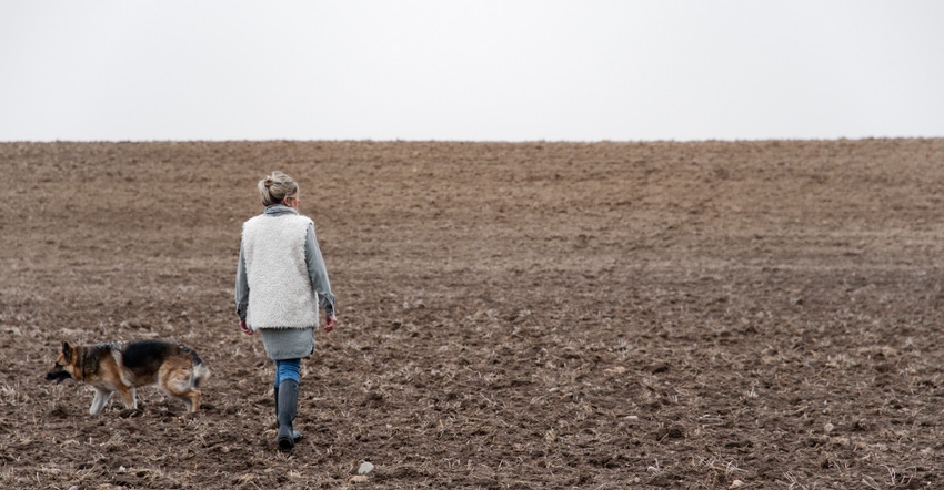 Woman walking in field with dog