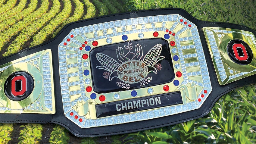 A championship belt with a corn and soybean field in the background