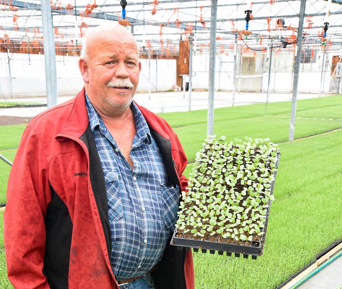 Daniel Riner, owner of Triple P Farms, holds up a tray of germinated coated seeds