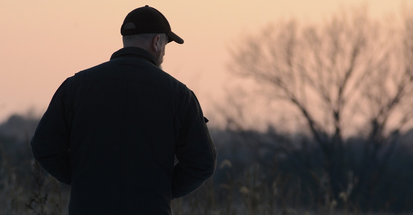 dark silhouette of farmer against horizon