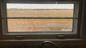A close up of a window looking out over farmland