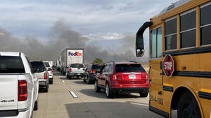 Cars stopped on an interstate because of black smoke seen on the horizon.
