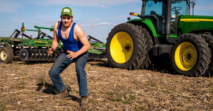 Jesse Wright takes a wrestling stance in front of a tractor