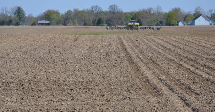 dirt field being prepared for planting with tractor in the background