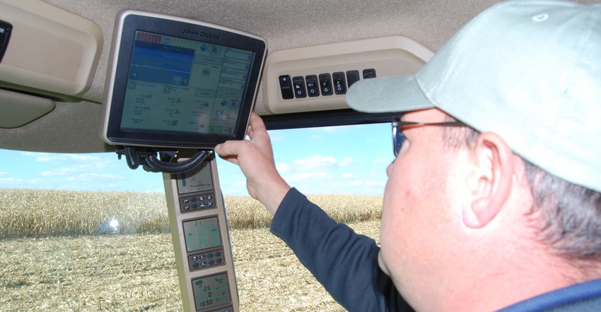 man looking at yield monitor in tactor cabin