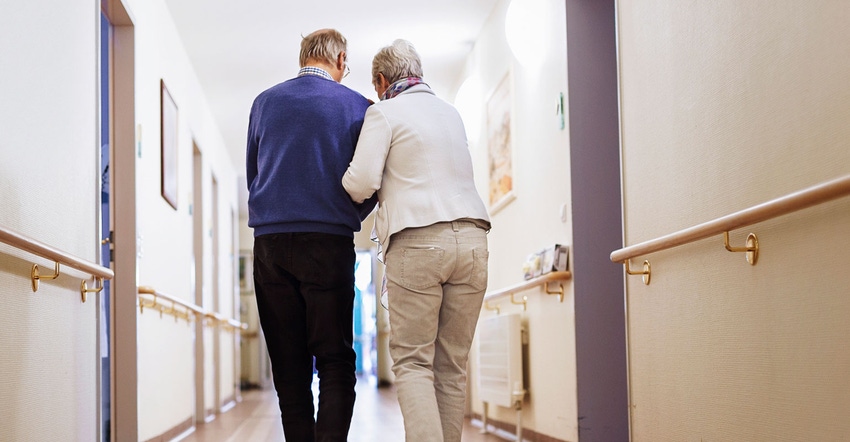 Senior couple walk hallway of care facility