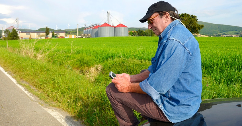 Farmer with tablet. Bins in the background