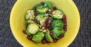 Brussel sprouts with pine nuts and pomegranate seeds in yellow bowl