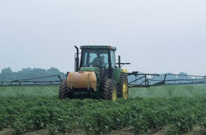 Tractor spraying cotton field with insecticide