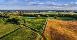 aerial drone photo over the fields and dirt road lanes in the fields against a blue sky